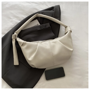 Close-up of creamy white pleated leather dumpling bag with textured lychee grain finish