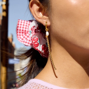 Dettaglio di eleganti orecchini in oro 18K con perla e nappina indossati dalla modella