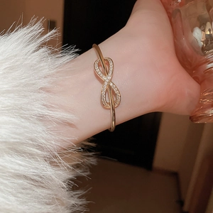 Close-up of gold infinity knot bracelet with sparkling cubic zirconia on model's wrist
