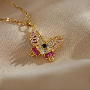 Detailed macro view of a gold butterfly pendant with pink and white micro-set gemstones