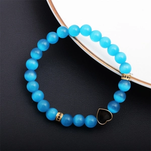 Macro shot of blue cat eye stone beads and gold heart charm with micro-pave detailing