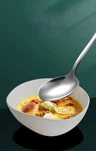 Macro detail of the rounded edge and wide bowl of a polished stainless steel soup spoon