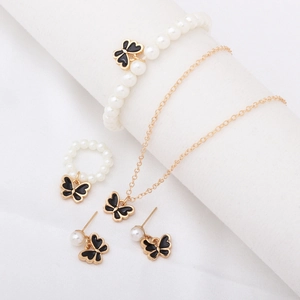 Parure de bijoux élégante avec pendentifs papillon noirs et perles blanches sur tissu