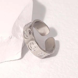 Detail eines silbernen Smiley-Rings auf weißem Stein mit polierter Metalloberfläche