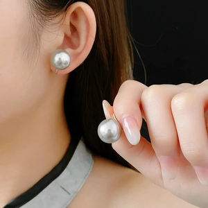 Macro shot of large grey pearl ear cuff with metallic luster on model ear