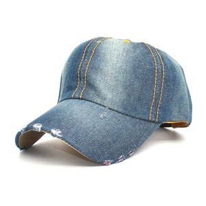 Detailed close-up of blue washed denim baseball cap with yellow stitching and distressed holes