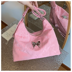 Detail of pink pleated nylon shoulder bag featuring a silver metal butterfly ornament