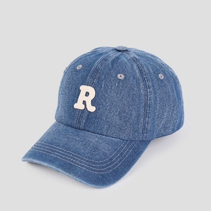 Detail of blue denim baseball cap featuring white towel embroidered R letter and top eyelets