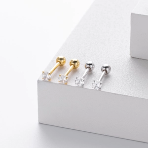 Macro shot of silver and gold screw stud earrings with cubic zirconia on white display