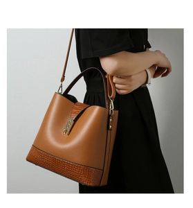 Detail of brown leather bucket bag featuring lychee and crocodile texture on model