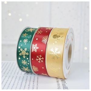 Close-up of green, red, and gold Christmas satin ribbons with gold snowflake and tree prints