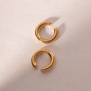Detail view of thick golden C-shaped hoop earrings with polished metallic finish