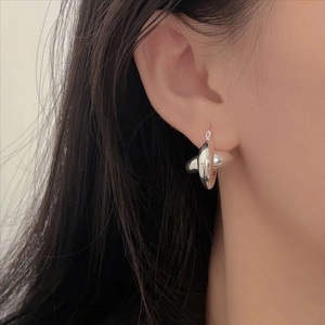 Minimalist 925 sterling silver crisscross hoop earrings on female model's ear