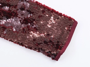Dettaglio delle paillettes bordeaux con polsini elastici a coste sulla manica
