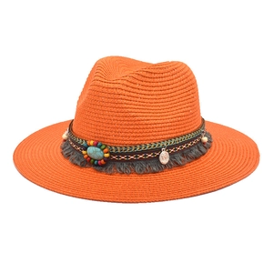 Detail of orange straw hat featuring an ethnic band with turquoise beads and tassels