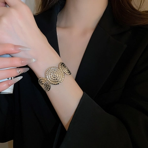 Detailed view of wide gold cuff bracelet featuring vintage spiral metallic textures