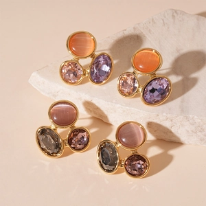 Boucles d'oreilles dorées avec pierres œil-de-chat colorées sur roche naturelle
