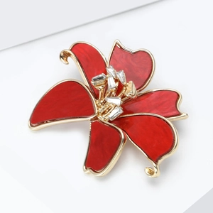 Detail of elegant lily brooch with red enamel petals, gold edges and crystal center
