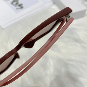 Detail view of burgundy and pink two-tone sunglasses showing the metal hinge and frame