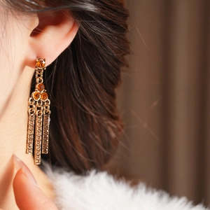 Close-up of vintage gold tassel earrings with amber stones and sparkling diamond accents