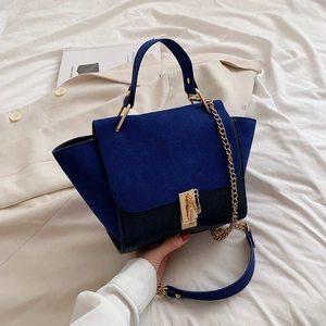 Close-up of blue suede and black crocodile pattern leather handbag with gold metal lock