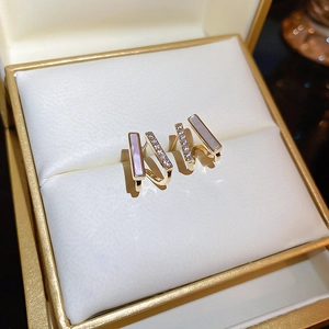 Detail showing gold earrings with white mother-of-pearl and zircon in a jewelry box