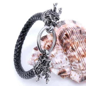 Detailed close-up of a woven leather bracelet with metal dragon head clasp on a seashell