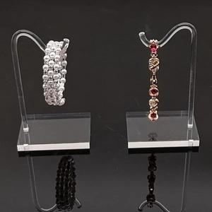 Acrylic jewelry display stand with white pearl bracelet and ruby heart pendant details