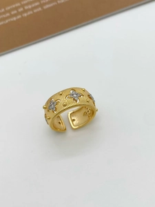 Macro detail of Italian brushed gold ring featuring sparkling star-shaped engravings