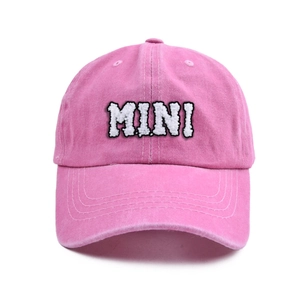 Close-up of pink cotton baseball cap with white MINI letter embroidery for children