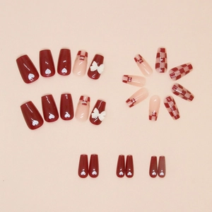 Close-up of red checkerboard press-on nails with white 3D bows and heart patterns