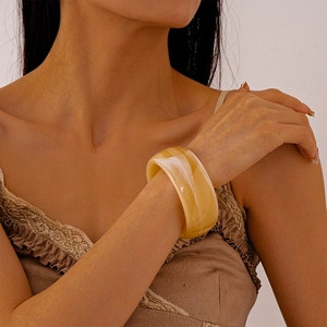 Macro detail of translucent amber striped acrylic resin bangle on model wrist