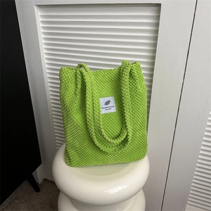 Vibrant green corduroy tote bag with textured finish and leaf-patterned label detail