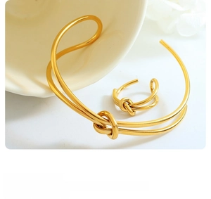 Detail showing gold knotted cuff bracelet and adjustable ring set on ceramic edge