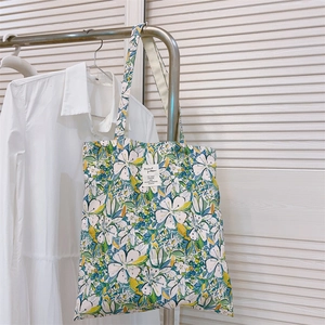 Dettaglio di una borsa tote in tela con vivace motivo floreale e patch centrale cucita