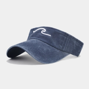 Détail de broderie vague blanche sur visière en denim bleu délavé pour sport de plein air