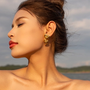 Close-up of 18K gold-plated double heart earrings worn by a model in natural sunset light