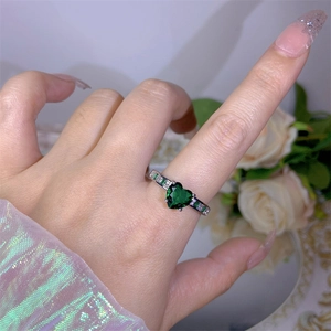 Close-up of a silver open ring featuring a large heart-shaped green emerald zircon stone