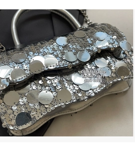 Close-up of silver sequin square bag featuring metallic ring handle and chain strap