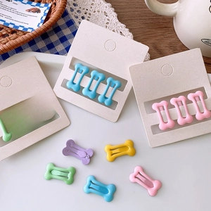 Macro detail of colorful bone-shaped metal hair clips on a premium accessories display card
