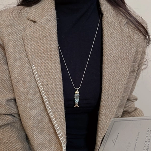 Detail of a gold fish pendant necklace with blue enamel scales on a model neck