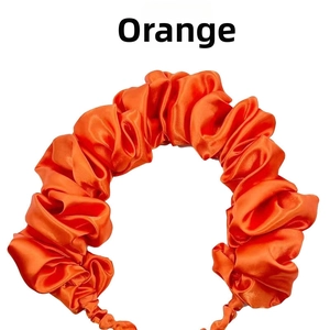 Close-up of bright orange pleated satin headband with silk-like elastic texture