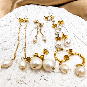Assorted 14K gold plated earrings with pearls on white stone and gold satin background