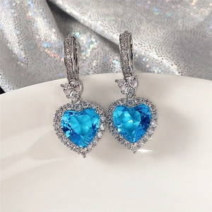 Close-up of heart-shaped blue topaz zircon earrings with silver hinge and clear accents