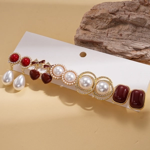 Détail d'un ensemble de 10 boucles d'oreilles avec perles en résine et nœuds en émail rouge