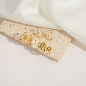 Three-piece gold plated earring set with cross charms, heart studs and polished C-hoops