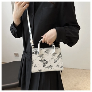 Dettaglio della mini borsa bianca con stampa a farfalla e tracolla rimovibile sulla modella