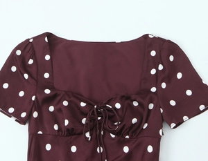 Detail of retro polka dot satin dress showing neckline tie and smooth fabric texture