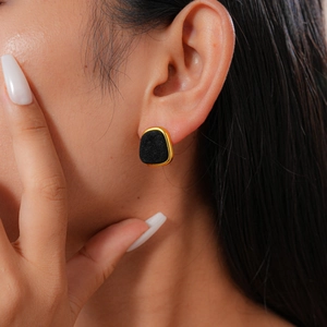 Close-up of a retro geometric earring with black flocking and gold-tone metal frame