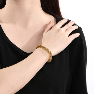 Close-up of golden braided dragon chain bracelet on wrist with high contrast lighting